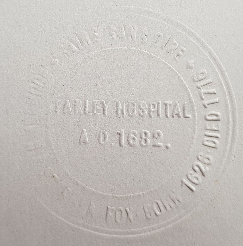 paper that has been stamped, some text not readable as the stamp is old, but which says "Farley Hospital A.D. 1682. Sir Stephen Fox. Born 1626. Died 1716." There is also some Latin which is not readable.
