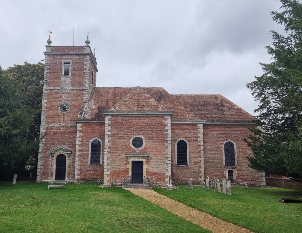 The front of Farley All Saint's church. A red brick building with tile roof, and clock tower
